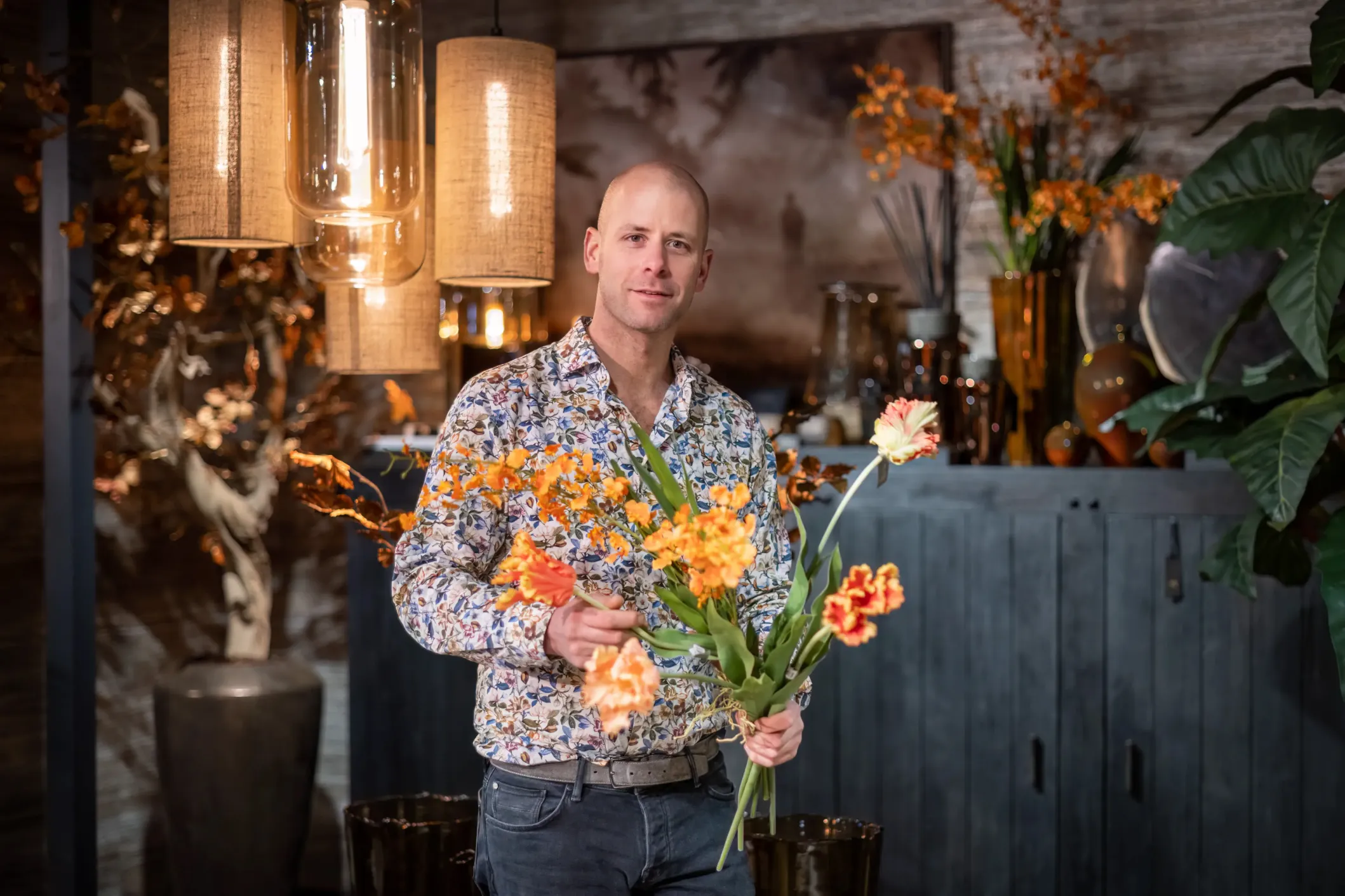 Bedrijfsfoto van een bloemist met een boeket oranje bloemen in zijn winkel