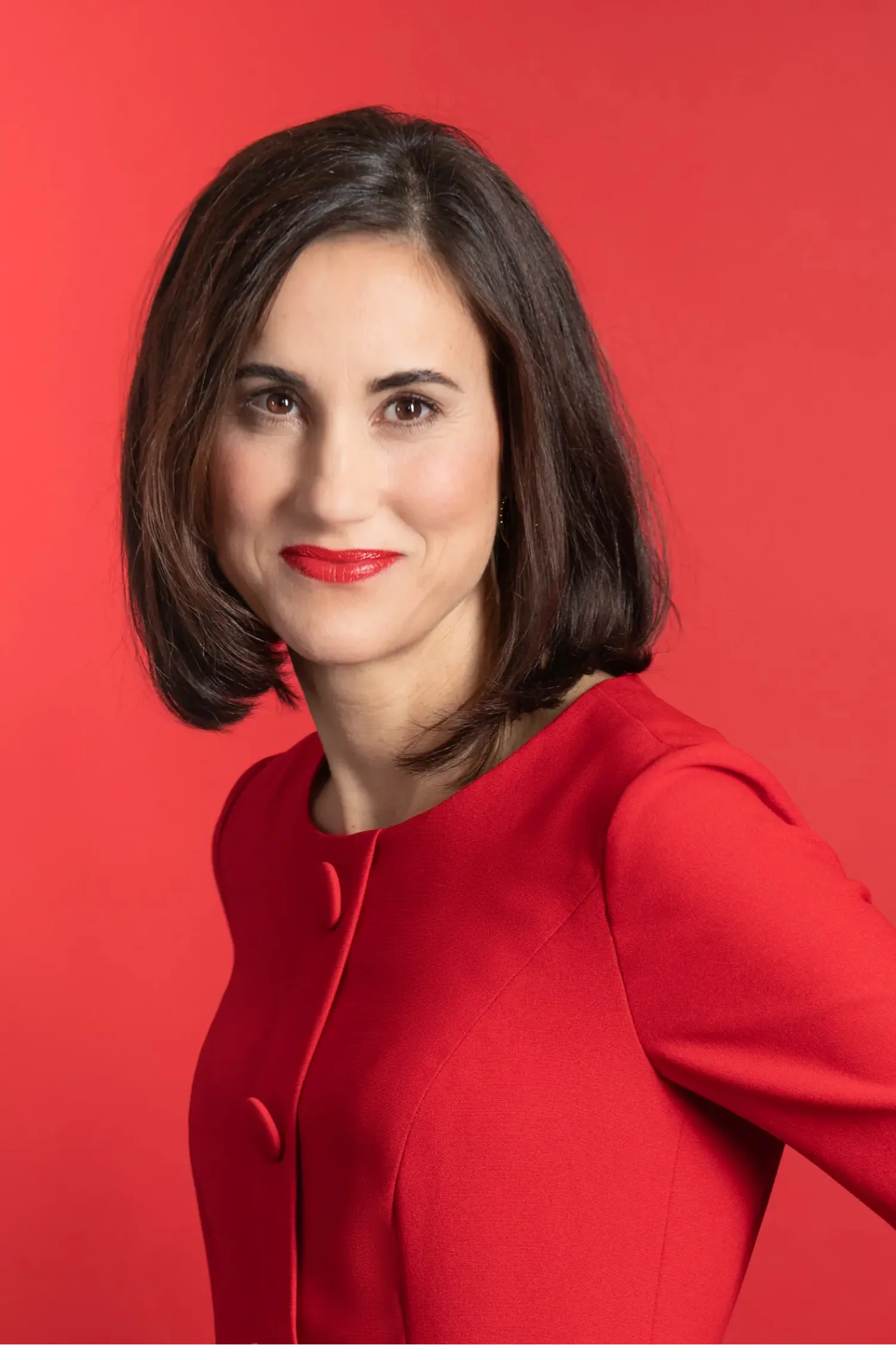 Zakelijk portret van een vrouw in het rood voor een rode achtergrond